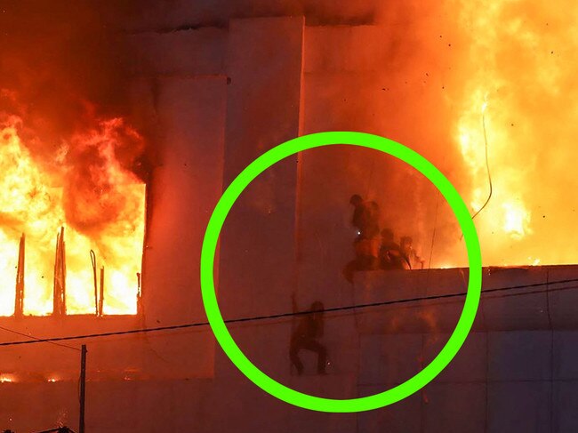 Fire burns near people on a ledge on the side of the Grand Diamond City hotel-casino in Poipet. Picture: AFP