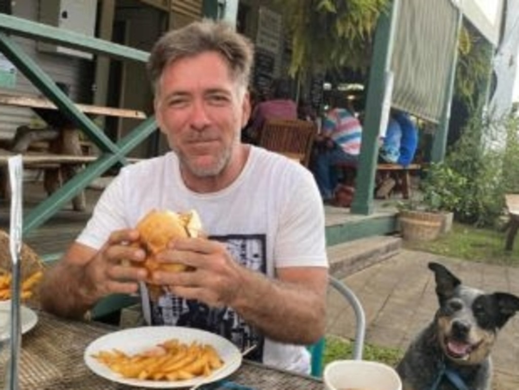 Safe and sound, Andrew Nielsen tucks into burger as his cattle dog Jasper looks on. Picture: Supplied