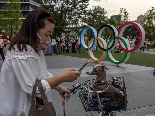 A woman prepares to photograph her dog next to the Olympic Rings in Tokyo as new coronavirus cases surge. Picture: Getty Images