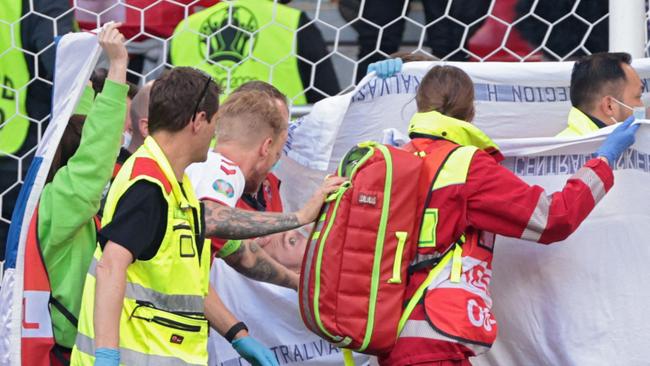 Denmark defender Simon Kjaer (left) checks on Christian Eriksen as paramedics carry him from the field. Picture: AFP