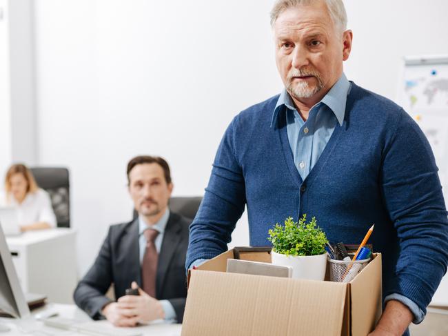 Quitting my responsibilities here. Fired involved aging employee standing and holding the box with his belongings while leaving the office