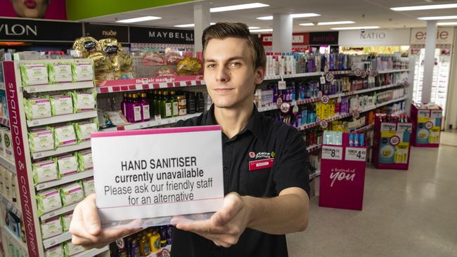 Priceline Alice Springs staff member Darcy McKinnon with a sign advising customers that hand sanitiser is not available for purchase. Picture: Kevin Farmer