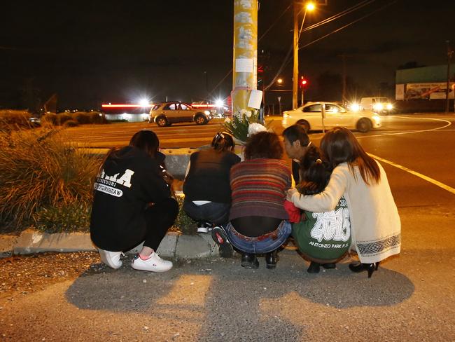 Aivy’s family huddle together after laying flowers and candles at the scene of the accident. Picture: David Caird