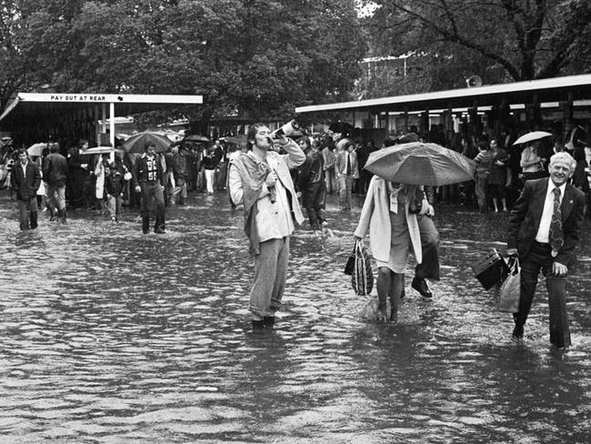 A punter finishes off his champagne despite the 1976 Melbourne Cup flood.