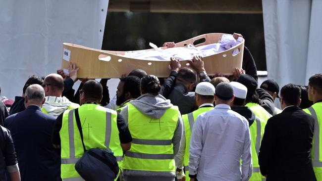 Mourners carry the first coffin of the Christchurch mosques massacre victim at Memorial Park Cemetery during the funeral ceremony in Christchurch on March 20, 2019. - As the first bodies of the Christchurch mosque shooting victims were returned to grieving families, Muslim volunteers from across New Zealand and Australia descended on the small town to help in the burial process. Islamic custom dictates that people have to be buried as soon as possible, but the scale and devastation of March 15's massacre -- that saw 50 killed in the usually quiet southern New Zealand city -- has delayed the handover of bodies to next of kin. (Photo by Anthony WALLACE / AFP)