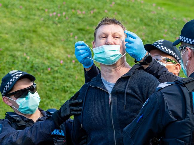 Police attempt to put a mask on a protester being arrested. Picture: Jake Nowakowski