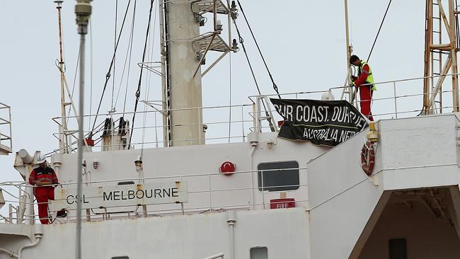 The new crew aboard CSL Melbourne remove protest signs. Picture: Peter Lorimer