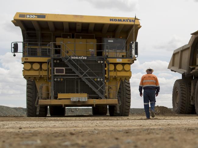 An employee walks towards Komatsu Ltd. 930E dump trucks at the Oyu Tolgoi copper-gold mine, jointly owned by Rio Tinto Group's Turquoise Hill Resources Ltd. unit and state-owned Erdenes Oyu Tolgoi LLC, in Khanbogd, the South Gobi desert, Mongolia, on Tuesday, June 17, 2014. Mongolia's Vice Minister for Mining Erdenebulgan Oyun said mining law amendments would increase Mongolia's area available to mining and exploration to 20 percent from around 8 percent, by lifting a 2010 ban on new licenses. The period of exploration would also increase from nine years to 12 years. Photographer: Brent Lewin/Bloomberg