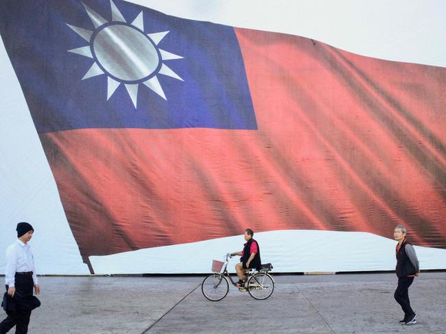 (FILES) People walk past a Taiwanese flag in New Taipei City on January 13, 2024. Taiwan's president-elect Lai Ching-te, a stanch defender of the island's democracy, will be sworn into office on May 20 as Beijing ratchets up military and diplomatic pressure on Taipei. (Photo by Sam Yeh / AFP)