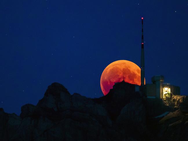 The moon turns red during a total lunar eclipse, behind the Saentis in Luzern, Switzerland. Picture: AP