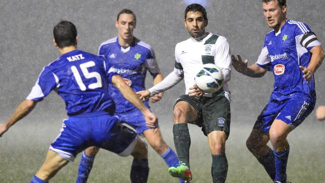 Hakoah players swarm a Northern Tigers player in torrential rain at Hensley Athletic Field.