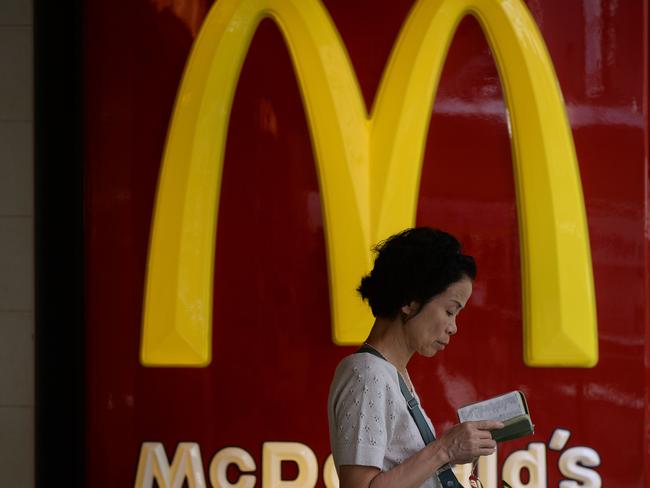 A woman reads outside a McDonald's fastfood restaurant in Hong Kong on July 28, 2014. McDonald's in Hong Kong on July 24 suspended sales of chicken nuggets and several other items including chicken burgers, salads and lemon tea after admitting it imported food from a US-owned firm in China at the centre of an expired meat scandal. McDonald's outlets in Beijing and Shanghai, it was reported on July 28, have yanked their flagship burgers off the menu after a key US supplier recalled products made by its Shanghai factory, which is alleged to have used expired meat. AFP PHOTO / DALE DE LA REY