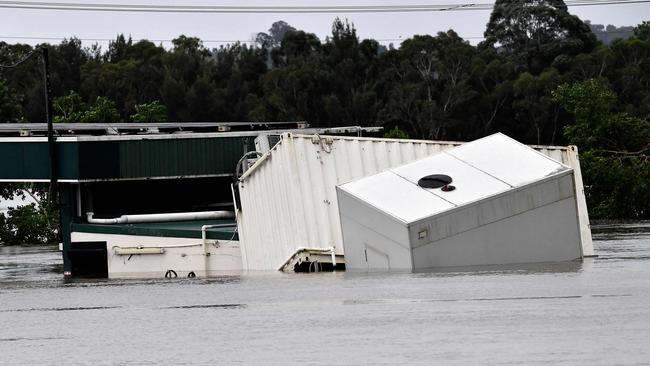 A container floats as rising floodwater inundated commercial area during heavy rain in southwestern suburb of Camden on March 8. Picture: Muhammad Farooq/AFP