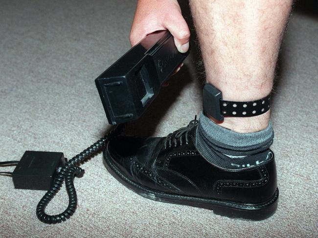 Electronic ankle bracelet, for use on criminals sentenced to home detention, when phone rings they have to put black device (in hand) on to electronic device on leg .  New South Wales (NSW) / Prison / Equipment