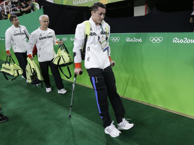 Germany’s Andreas Toba, who got injured during the qualification round, walk in with the help of crutches during the artistic gymnastics