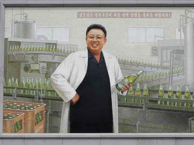 A mural of the late North Korean leader Kim Jong Il in a white lab coat holding up a bottle of beer is seen at the entrance of the Taedonggang Brewery in Pyongyang. Picture: Wong Maye-E/AP