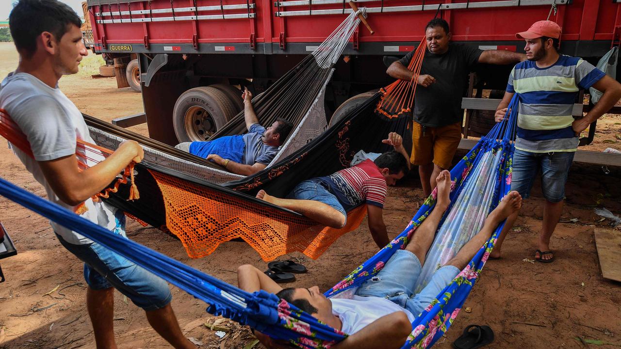 Brazilian trucker Erik Fransuer (left) speaks with truckers resting on hammocks at a gas station, in Ruropolis, Para state, Brazil. Fransuer loves the freedom of the road. (Photo by Nelson Almeida/AFP)