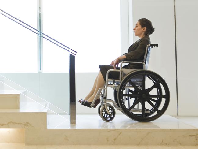 Generic image of disabled businesswoman sitting in a wheelchair, debating how to get up the stairs to work.