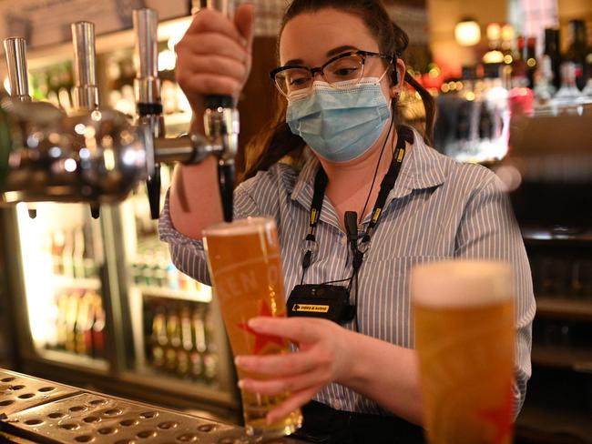 A member of the bar staff pulls a pint in a Wetherspoons pub in Leigh, Greater Manchester, northwest England on October 22, 2020 ahead of new coronavirus restrictions coming into force in the area. - British Prime Minister Boris Johnson imposed tougher coronavirus restrictions on an area of the northewest of England after placing Greater Manchester into the government's tier 3, the highest coronavirus alert level, defying local leaders who bitterly opposed the move without extra funding. The extra restrictions which servely limits social mixing in hospitality venues will come into effect on October 23, 2020. (Photo by Oli SCARFF / AFP)