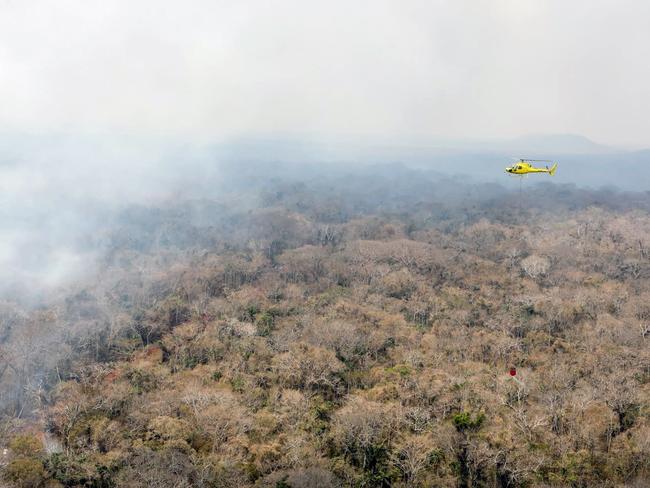 (FILES) In this ahndout file photo taken on September 19, 2019 released by France's Ministry of Europe and Foreign Affairs, a helicopter sprays water to extinguish a fire near San Ignacio de Velasco, Santa Cruz, Bolivia, south of the Amazon basin. - French oil company Total suspended operations in a natural gas field in Bolivia due to security issues regarding wildfires, informed the company of October 1, 2020. (Photo by Jonathan SARAGO / FRANCE'S MINISTRY OF EUROPE AND FOREIGN AFFAIRS / AFP) / RESTRICTED TO EDITORIAL USE - MANDATORY CREDIT "AFP PHOTO / MINISTRY OF EUROPE AND FOREIGN AFFAIRS / Jonathan SARAGO" - NO MARKETING - NO ADVERTISING CAMPAIGNS - DISTRIBUTED AS A SERVICE TO CLIENTS