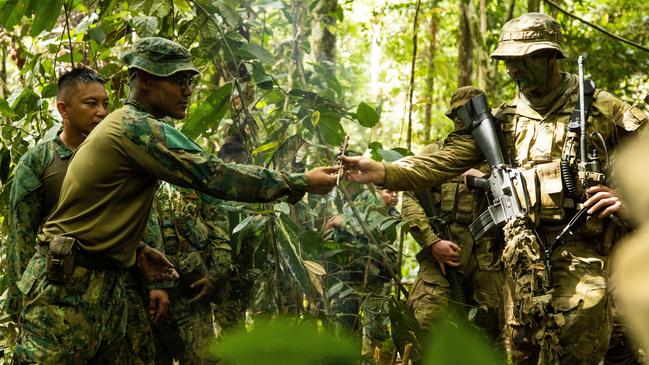 Royal Brunei Land Force officer Lieutenant Ziam shares caught and cooked food with Australian Army soldier Lance Corporal Brodie Forrest in Brunei. Picture: Guy Sadler.