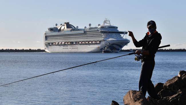 A fisherman set against the Ruby Princess carrying crew only onboard docks at Port Kembla, Wollongong, on Monday morning.