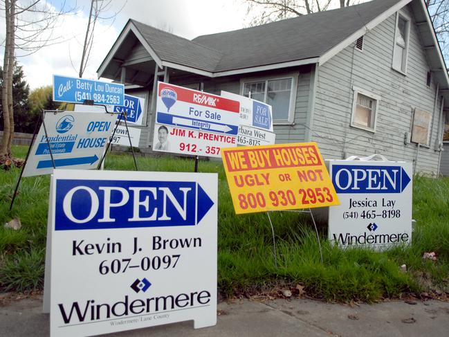 For sale and open house signs are clustered in the front yard of a street corner home in Eugene, Oregon Sunday, March 18, 2007. Sales of previously owned homes in the U.S. unexpectedly rose 3.9 percent in February, the biggest monthly gain in almost three years, a sign the housing market is recovering even as lending standards tighten. Photographer: Ty Wright/Bloomberg News.