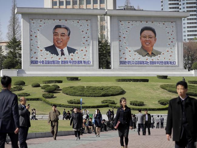North Koreans walk along downtown Pyongyang where portraits of the late leaders, Kim Il Sung, left, and Kim Jong Un, are seen in the background. Picture: AP