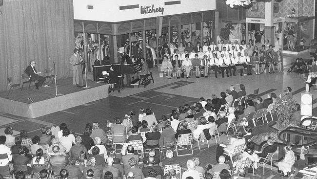 Shoppers sit on folding chairs for an event in the Centre Court at Marion in the 1970s. In the background is Witchery and Sussan.