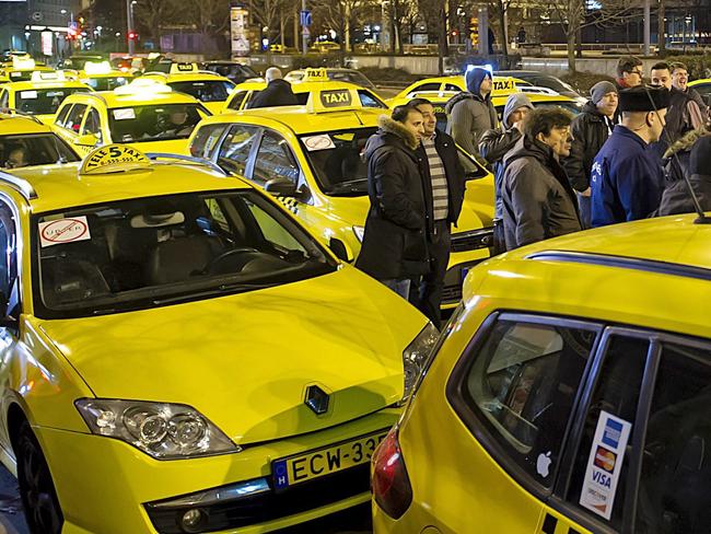 Taxi cab drivers gather by their vehicles at Erzsebet Square during an unannounced demonstration against the use of Uber rideshare application in the early morning hours in downtown Budapest, Hungary, Monday, Jan. 18, 2016. (Peter Lakatos/MTI via AP)