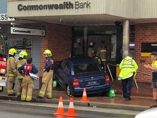 A car mounted the steps of Maclean's Commonwealth Bank and momentarily pinned an 81-year-old woman this morning.