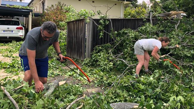 Mark and Natalie Gauci clearing the front of their home in Wareham Crescent, Frenchs Forest, after a violent storm swept through. Picture: Jim O'Rourke.