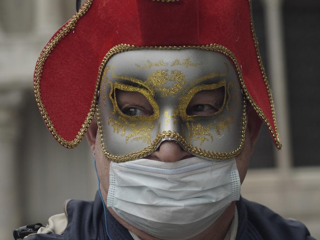 A Russian tourist dons both a carnival mask and a protective face mask as he visits St Mark's square in Venice. Picture: Renata Brito/AP