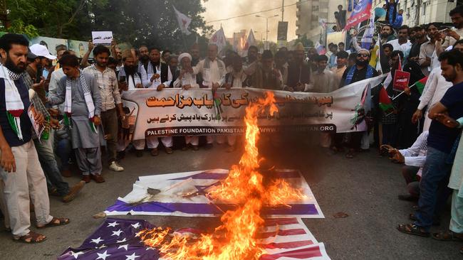 Protesters burn the national flags of US and Israel during an anti-Israel demonstration in Karachi on October 8. (Photo by Asif HASSAN / AFP)