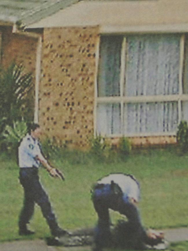 A police officer keeps the gun trained on Omar Baladjam after he was shot. Picture: Hearne Bill