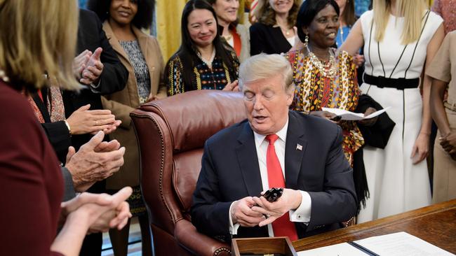 US President Donald Trump hands out pens after signing a presidential order during an event to launch the Women's Global Development and Prosperity Initiative in the Oval Office of the White House February 7, 2019 in Washington, DC. (Photo by Brendan Smialowski / AFP)