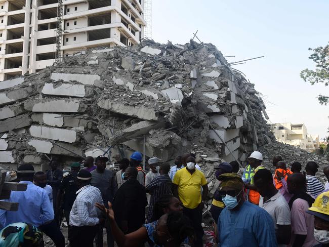 TOPSHOT - People stand to look at the rubble of a 21-storey building under construction that collapsed in the Ikoyi district of Lagos, on November 1, 2021. - Several people have been trapped while unspecified number of people mostly construction workers were feared dead as a 21-storey building suddenly collapsed in the Ikoyi district of Lagos, Nigeria's commercial capital. (Photo by PIUS UTOMI EKPEI / AFP)