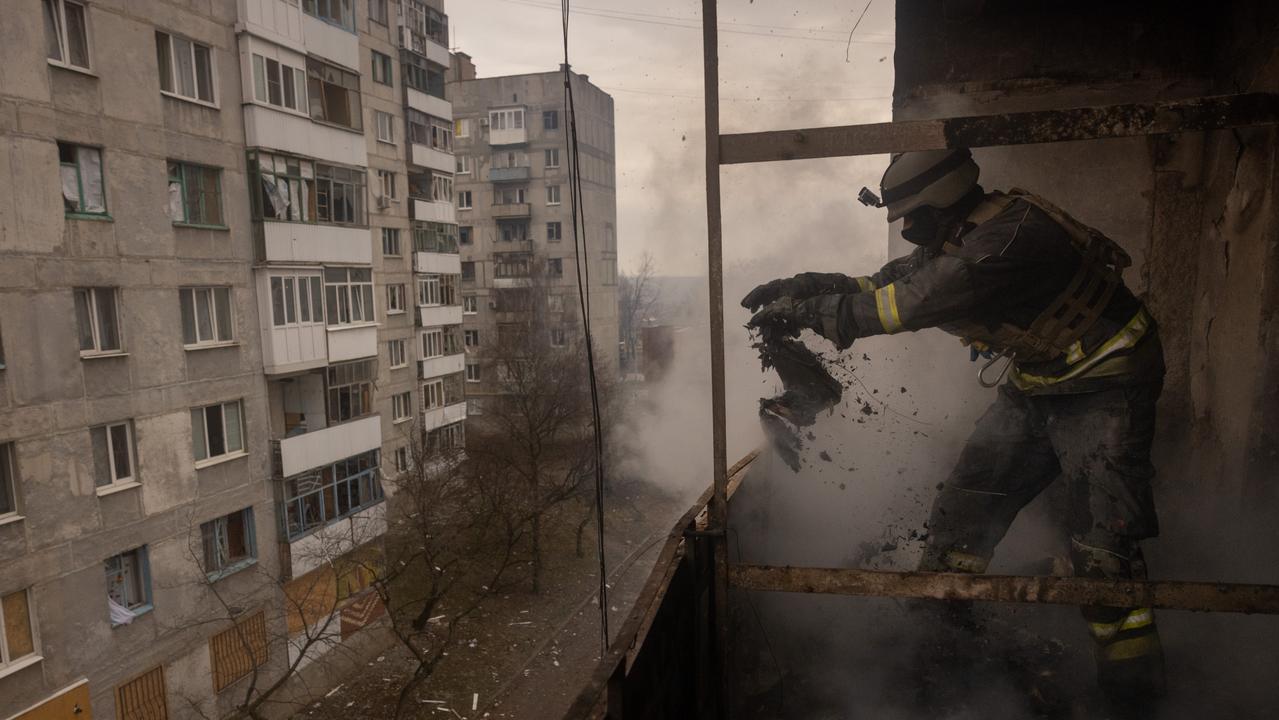 A Ukrainian emergency service worker throws flammable debris from the balcony of an apartment while working to extinguish a fire in a high rise residential building that was hit by Russian shelling on December 12, 2022 in Bakhmut, Ukraine. Picture: Chris McGrath/Getty Images