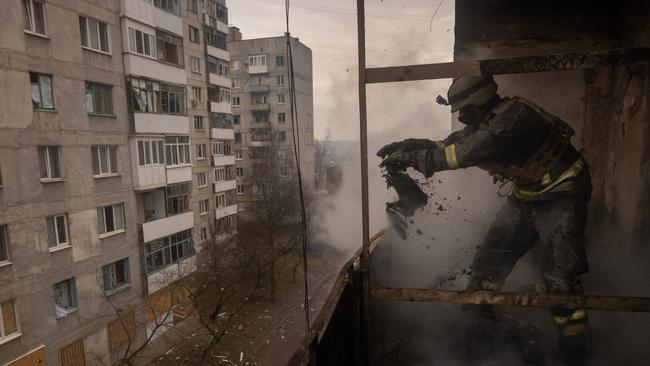 A Ukrainian emergency service worker throws flammable debris from the balcony of an apartment while working to extinguish a fire in a high rise residential building that was hit by Russian shelling on December 12, 2022 in Bakhmut, Ukraine. Picture: Chris McGrath/Getty Images