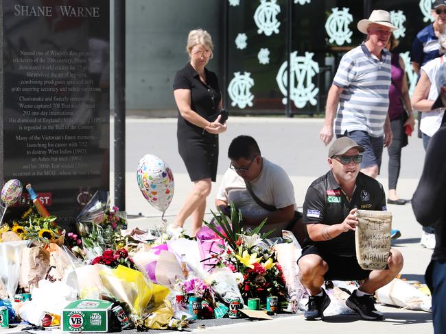 People continue to place flowers and other items at the Shane Warne statue at the MCG days after his death in Thailand. Picture: NCA NewsWire / David Crosling.