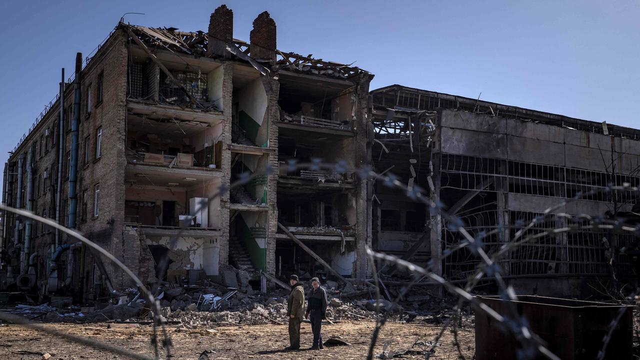 People stand beside damaged buildings at the Vizar company military-industrial complex, after the site was hit by overnight Russian strikes, in the town of Vyshneve, southwestern suburbs of Kyiv, on April 15, 2022. Picture: Fadel Senna/AFP