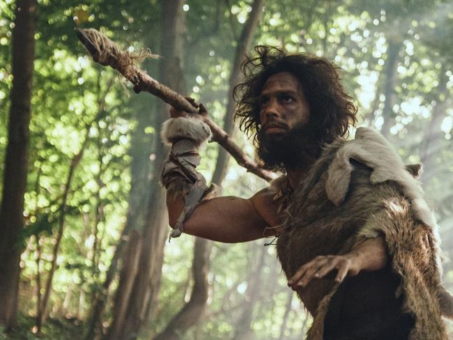 Primeval Caveman Wearing Animal Skin Holds Stone Tipped Spear Looks Around, Explores Prehistoric Forest in a Hunt for Animal Prey. Neanderthal Going Hunting in the Jungle