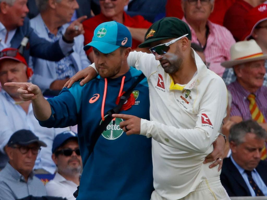 Nathan Lyon being helped from the field by Australian team physio Nick Jones. Picture: Ian Kington / AFP