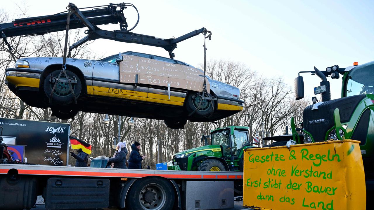 Anti-government slogans are written on a car hanging from a vehicle transporter. Right banner reads: 