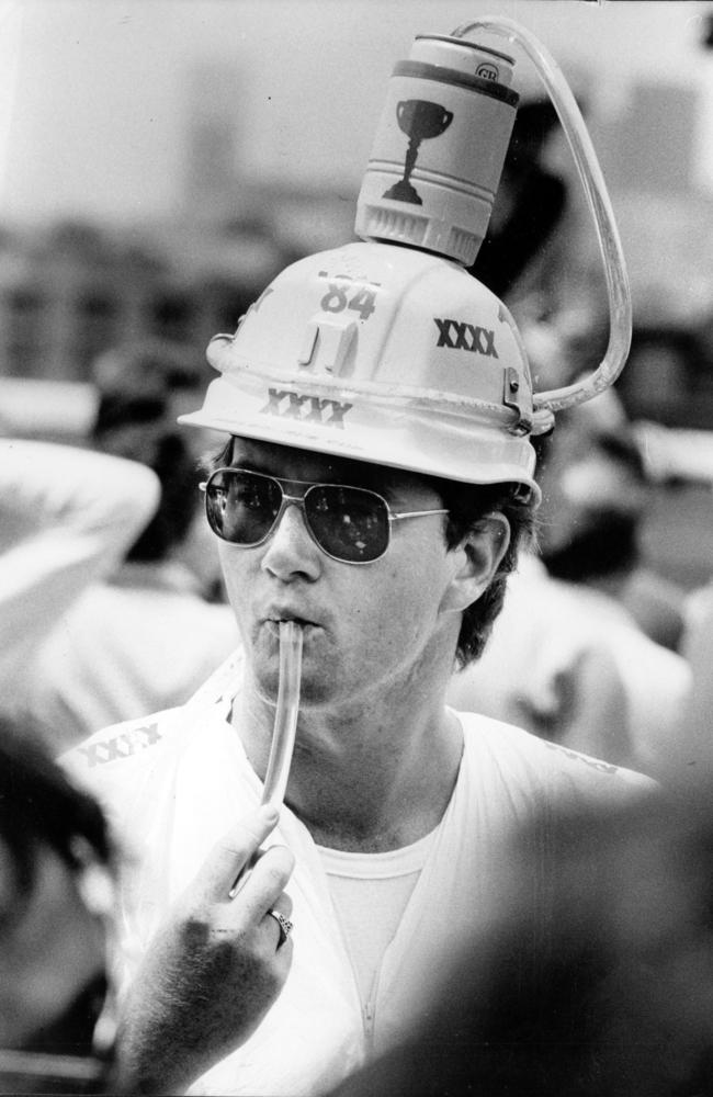 A man drinks from a beer hat in 1984.