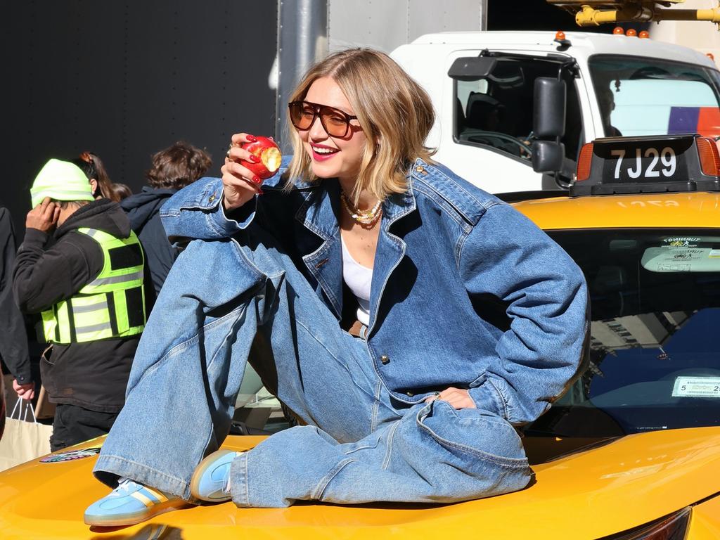 Elsewhere in the world, supermodel Gigi Hadid made eating an apple on the hood of a taxi look completely natural as she filmed a commercial for Maybelline in New York City. Picture: Splash/Backgrid