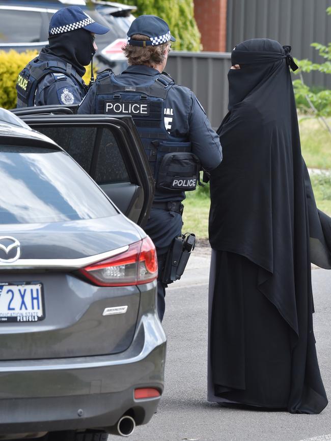 Police talk to a woman near a roadblock during a raid in Meadow Heights linked to the Bourke Street attack. Picture Jay Town