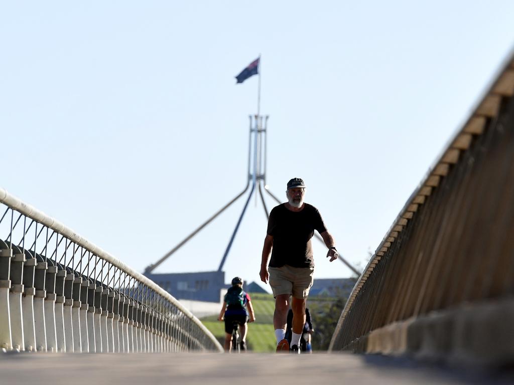 CANBERRA, AUSTRALIA - MARCH 20: Parliament House is seen behind as people exercise near Lake Burley-Griffin on March 20, 2020 in Canberra, Australia. The Australian government has banned non-essential gatherings of 100 or more people indoors, along with outdoor gatherings of more than 500 people in a bid to contain the spread of COVID-19. Prime Minister Scott Morrison on Thursday announced Australia would be closing its borders to all visitors for six months. The travel ban will be placed on all people who are not Australian residents or their direct relations coming to the country from 9pm on Friday night.  There are now 756 confirmed cases of COVID-19 In Australia while the death toll now stands at seven. (Photo by Sam Mooy/Getty Images)