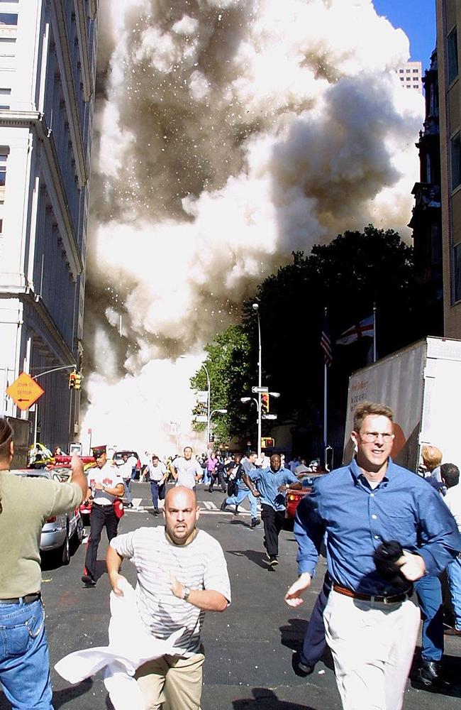 Pedestrians run from the scene as one of the World Trade Center Towers collapses. Picture: Doug Kanter