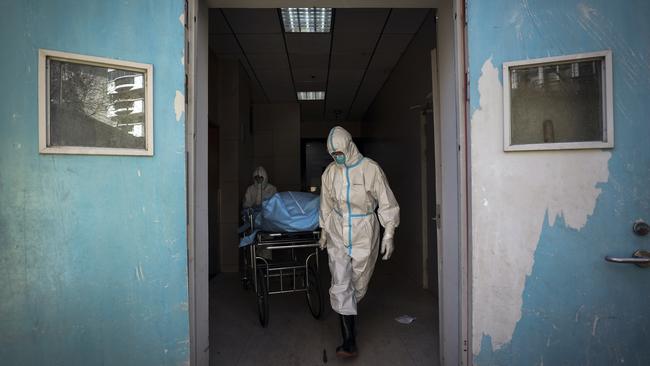 Medical workers move a person who died from COVID-19 at a hospital in Wuhan in central China's Hubei province.